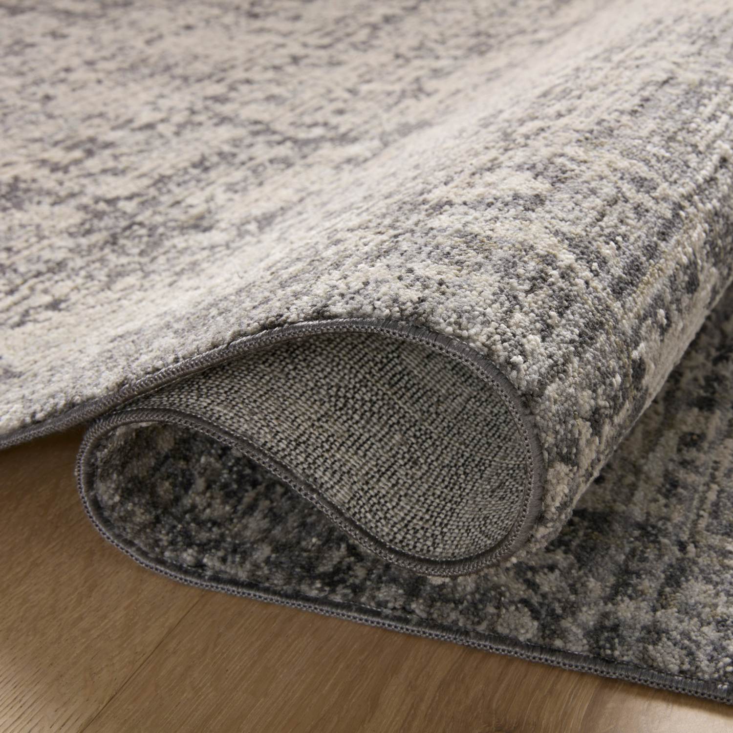 Edge and backing detail of Homvirex Alie Charcoal Dove rug